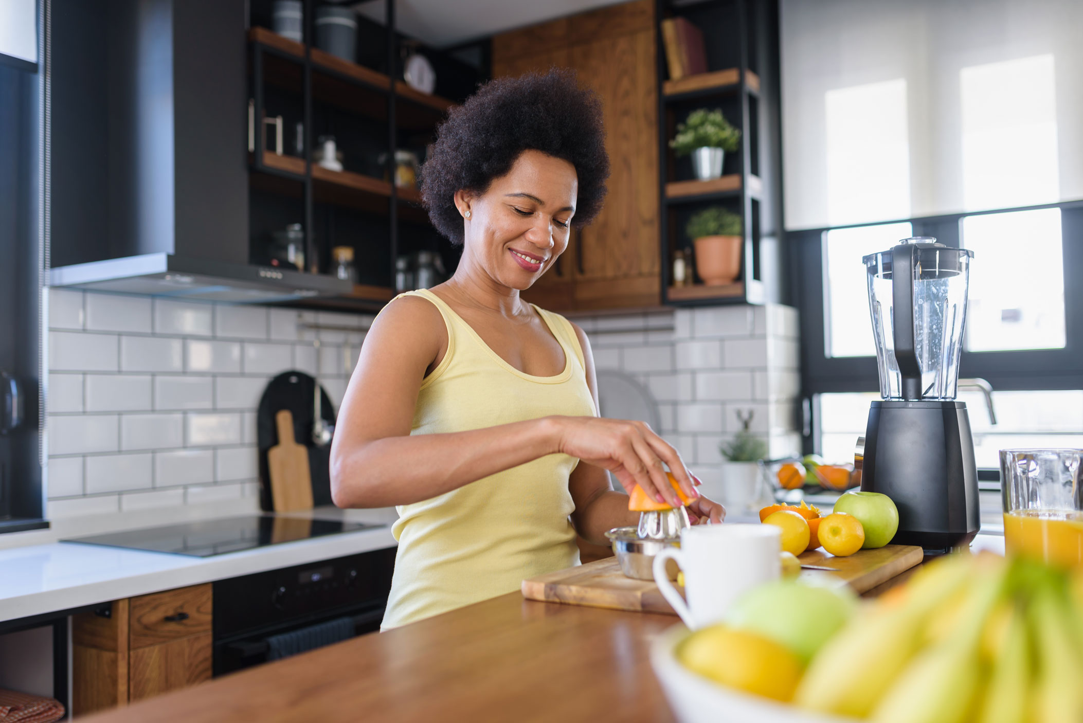 8f79e1adae8040c9cd15ac3250fb8c80 Image of a woman juicing an orange, illustrating the concept incorporating eating healthily while taking injections for weight loss