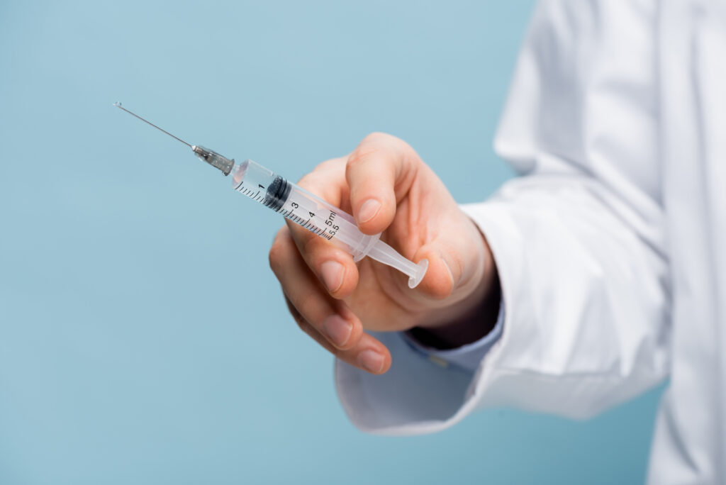 A doctor's hand holding a syringe, representing the concept of weight loss injections for men.