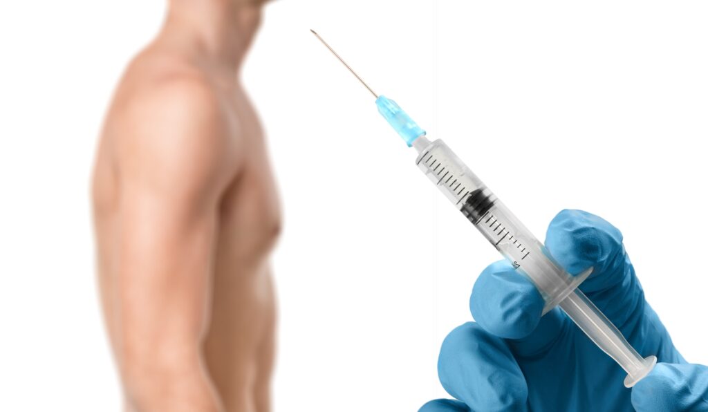 The hand of a doctor holding a syringe, with a man out of focus in the background, symbolizing the administration of weight loss injections for men.