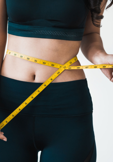 Woman measuring her waist, suggesting progress or interest in injections for weight loss